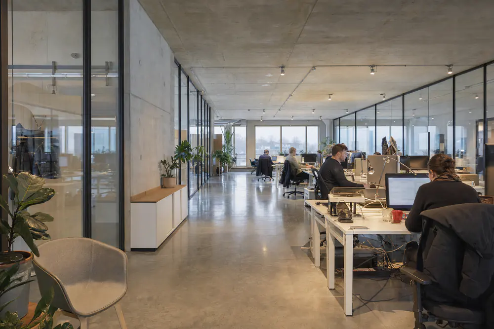 Onbehandelde kantoorvloer met betonplafond, glazen wanden en een betonvloer