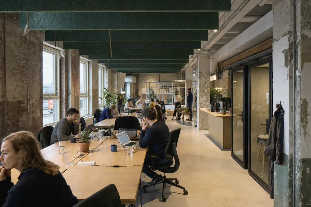 Coworkingruimte in een oud industriegebouw met groene vilten baffles en belcellen