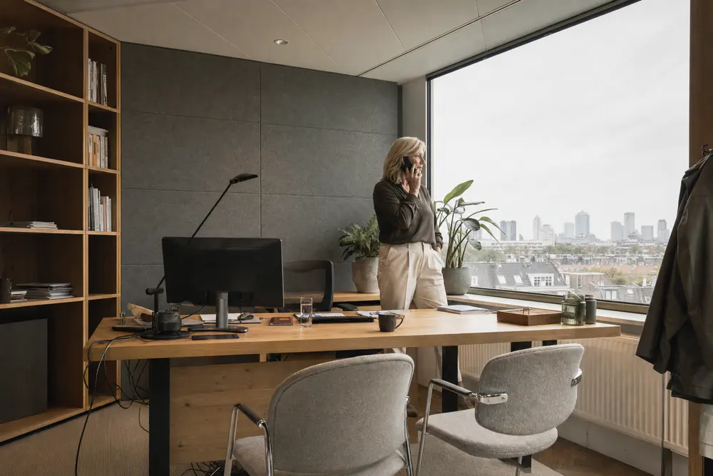 Directiekamer met een wand van grijze viltpanelen achter het bureau