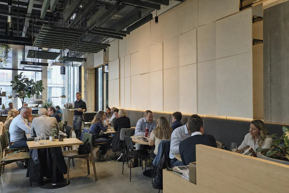 Lunchrestaurant met groene vilten baffles en een akoestische wand boven de bank