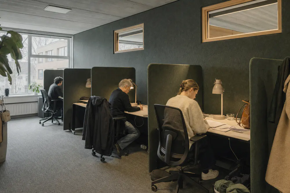 Stilteruimte met losse werkplekken tussen hoge vilten zijpanelen